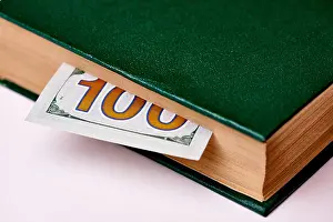 Economical Prints: Bill worth one hundred US dollars in book on a white background macro