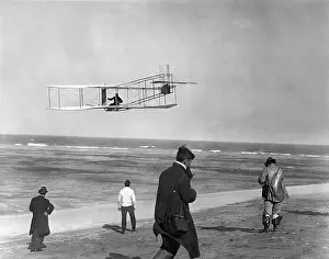 Hars Prints: ONE OF THE WRIGHT BROTHERS FLYING GLIDER BY THE OCEAN AND SPECTATORS ON BEACH BELOW KITTY HAWK NORTH CAROLINA USA