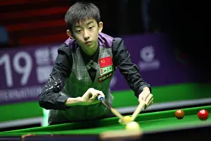 Snooker Prints: Wu Yize of China plays a shot to John Higgins of Scotland in the heldover match during the 2019 World Snooker