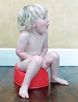 Stressful Prints: Two year old child sitting on red potty looking off camera