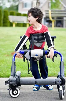 Disability Prints: Five year old disabled boy in walker by park. He has cerebral palsy