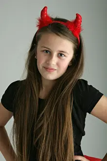 Looking At Camera Prints: Ten year old girl wearing red devil horns fancy dress