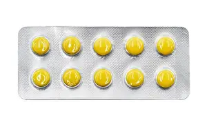 Yellow pills in blister pack isolated on white background. Global pharmaceutical industry. Closeup, top view