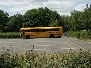 Summer Trees Prints: A Yellow School Bus parked in an empty coach park.