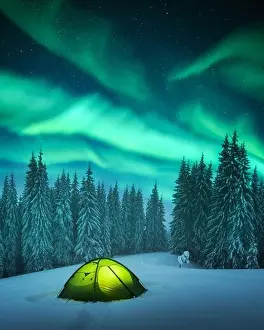 Yellow tent lighted from the inside against the backdrop of incredible starry sky with Aurora borealis. Amazing night landscape