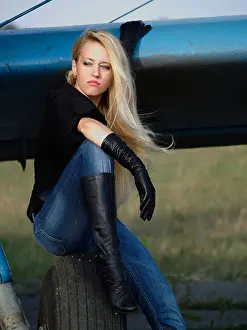 Staring Prints: Youg blond woman sitting on vintage airplane landing gear