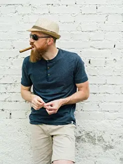 Cigar Prints: Young adult male wearing fedora and sunglasses smoking a cigar on the street