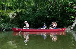 Three young adults in family paddling in a canoe on the Royal River in Yarmouth Maine, summer, USA
