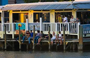 Dine Prints: Young adults sitting on dock at Pops Sunset Grill outdoor restaurant on the Gulf Intercoastal Waterway in Nokomis