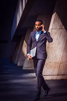 Young African American businessman with beard talking on cell phone