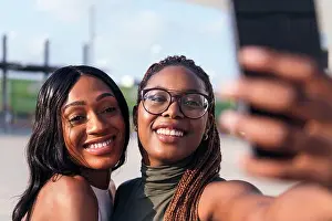 Selfie Prints: two young african friends smiling happy to take a selfie photo with a cell phone
