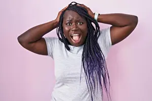 Shocked Prints: Young african woman standing over pink background crazy and scared with hands on head