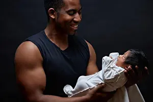 Young afro-american daddy holding his sweet newborn baby in the arms and looking at him with love. side view photo. first meeting with a adorable baby