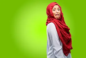 Disgust Prints: Young arab woman wearing hijab feeling disgusted with tongue out