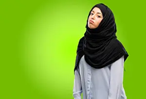 Fatigue Prints: Young arab woman wearing hijab with sleepy expression, being overworked and tired