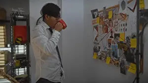 Evidence Prints: A young asian man drinks coffee in a detective's office