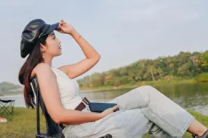 Yogyakarta Prints: Young Asian woman wearing a hat and sitting on a chair by a lake