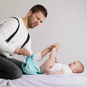 Cuddling Prints: Young attractive father is changing nappy to his baby girl