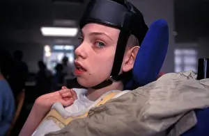 Difficulties Prints: Young autistic boy in wheelchair wearing protective head gear at a special school London UK