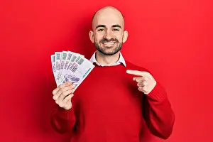 Bald Prints: Young bald man holding egyptian pounds banknotes smiling happy pointing with hand and finger