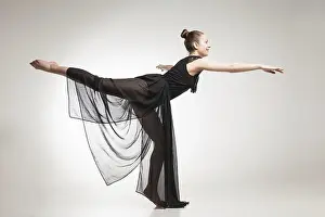Against White Background Prints: Young ballet dancer wearing black transparent dress dancing over white background