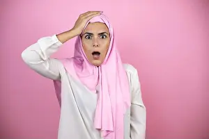 Business Man Prints: Young beautiful arab woman wearing islamic hijab over isolated pink background putting one hand on her head smiling