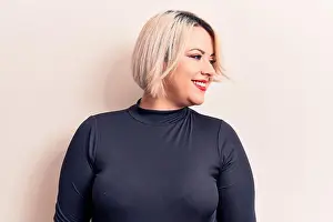 Plus Size Prints: Young beautiful blonde plus size woman wearing casual sweater over isolated white background looking to side