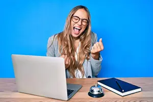 Triumph Prints: Young beautiful blonde woman sitting at hotel reception celebrating surprised
