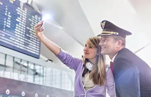 Taking Prints: Young beautiful teenage girl taking selfie with mature pilot in airport