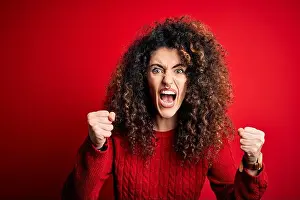 Fist Prints: Young beautiful woman with curly hair and piercing wearing casual red sweater angry