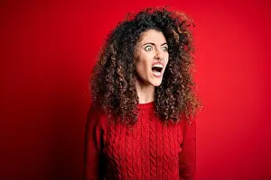 Rage Prints: Young beautiful woman with curly hair and piercing wearing casual red sweater angry and mad screaming frustrated