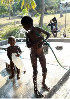 Haiti Prints: A young black child plays and washes with clean water while a smiling mum looks on