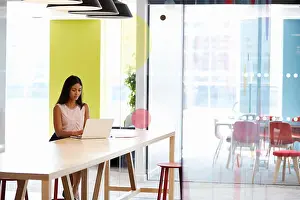 Concentrating Prints: Young black woman working alone in an office meeting area