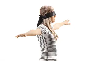 Afraid Prints: Young blond woman wearing blindfold and walking with spread arms isolated on white background