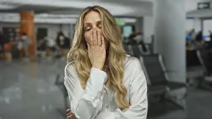 Exhausted Prints: Young blonde woman in an airport terminal looking tired indoors with eyes closed