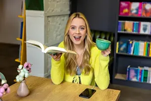Bookstore Prints: Young blonde woman drinking coffee with a book