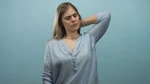 Calmness Prints: Young blonde woman touches neck with closed eyes in studio against light blue background; serenity reflection