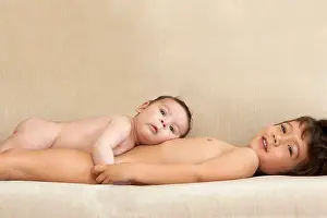 A young boy and his baby brother lying on the couch