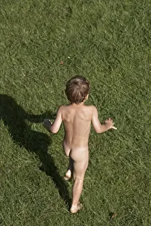 Young boy child playing from above running away in a suburban garden in summer London England UK Naked nude or bare CJWH
