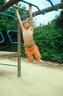 12 13 Years Prints: a young boy climbing along monkey bars on a playground