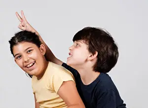 Young boy and girl playing, young boy holding up fingers as rabbit ears
