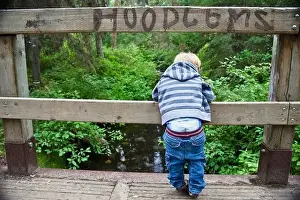 Contentment Prints: Young Boy Looking Over A Bridge With His Pants Falling Down And The Sign Hoodlums Over His Head