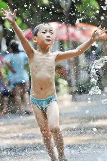 Heat Wave Prints: A young boy plays with water to cool down in a fountain on a scorching day in Hangzhou city