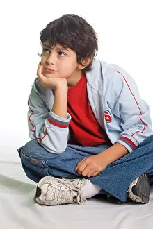 Wishing Prints: Young boy sitting down on the floor in a thoughtful pose Studio shot isolated on white background