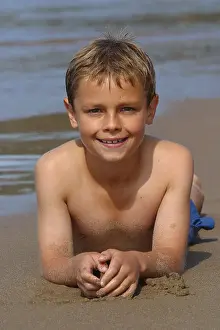 Preteen Prints: Young boy white caucasian aged 10 years old lying on sand beach sea shoreline