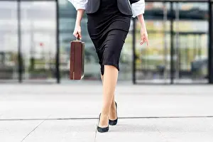 Part Of Prints: Young businesswoman wearing high heels walking with briefcase on footpath