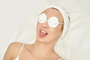 Masks Prints: Young caucasian female relaxing in spa with eye masks and sticking tongue out