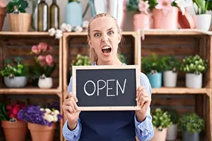 Flower Shop Prints: Young caucasian woman working at florist holding open sign angry and mad screaming frustrated and furious