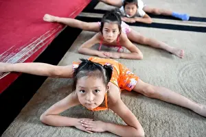 Young Chinese girls bend their bodies and do the splits on the floor to practice gymnastics at a gymnastics training center in Bozhou city, east China