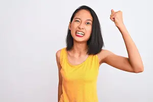 Fist Prints: Young chinese woman wearing yellow casual t-shirt standing over isolated white background angry